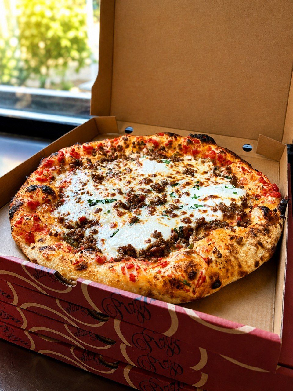 Pizza à la viande hachée, mozzarella et basilic frais dans sa boîte ouverte